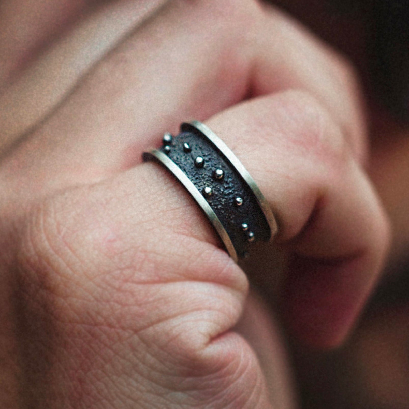 Cool ring with a black texture in the middle and some silver dots on top, acompanied with a silver border